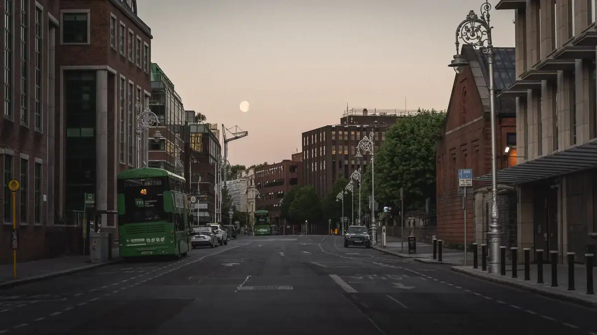 Early morning in Dublin around 5 AM — the sun’s coming up, the moon’s still visible, and the streets are mostly empty except for locals heading to work. A quiet, calm moment to explore the city.