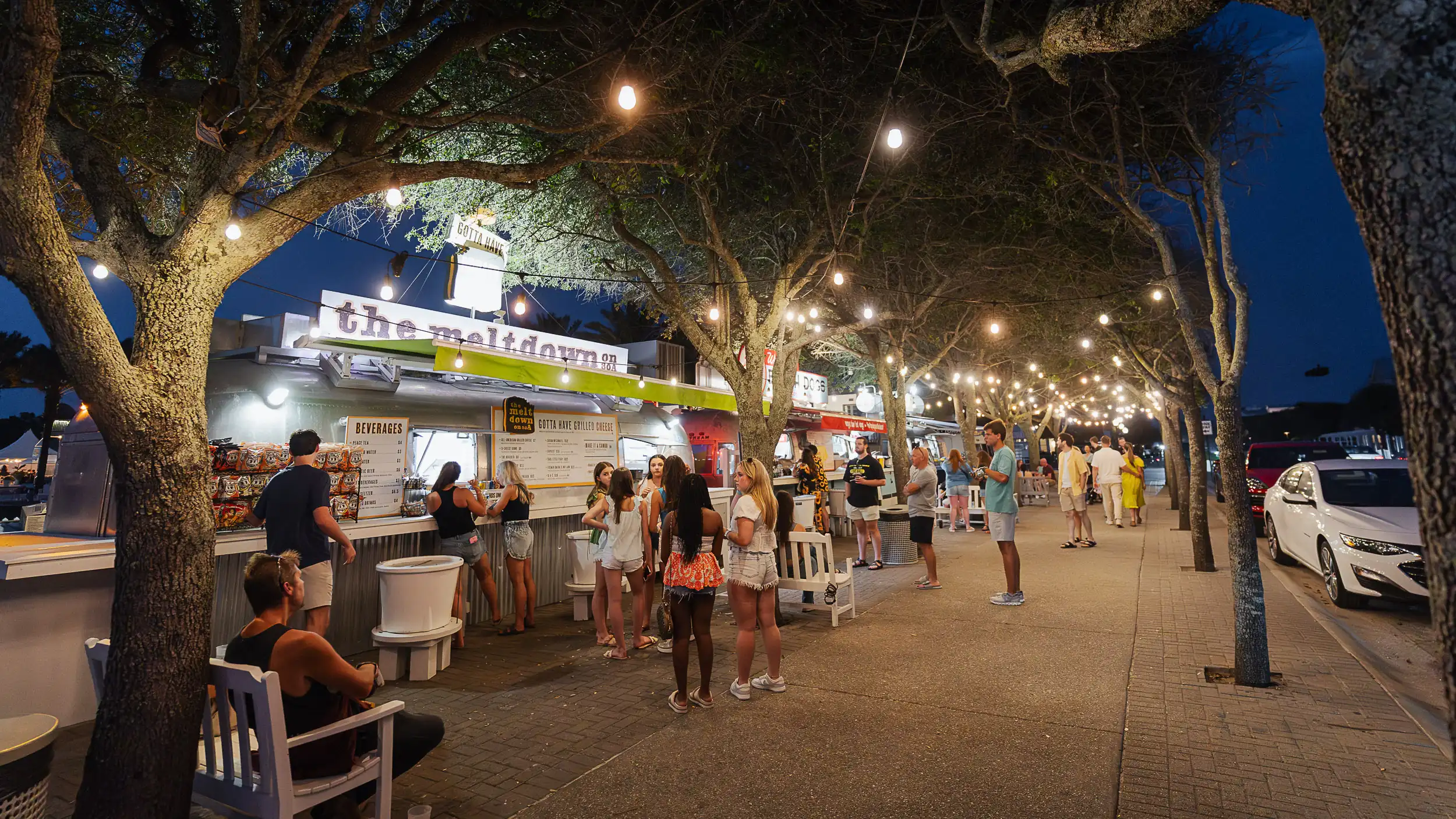Lively nighttime scene at Seaside food trucks with people enjoying food, music, and hanging out.