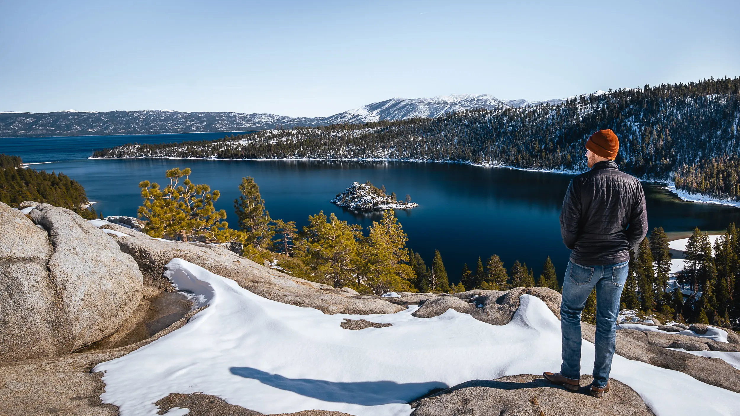 Scenic winter overlook at Emerald Bay featuring fresh snow, icy water, and a person viewing the landscape.