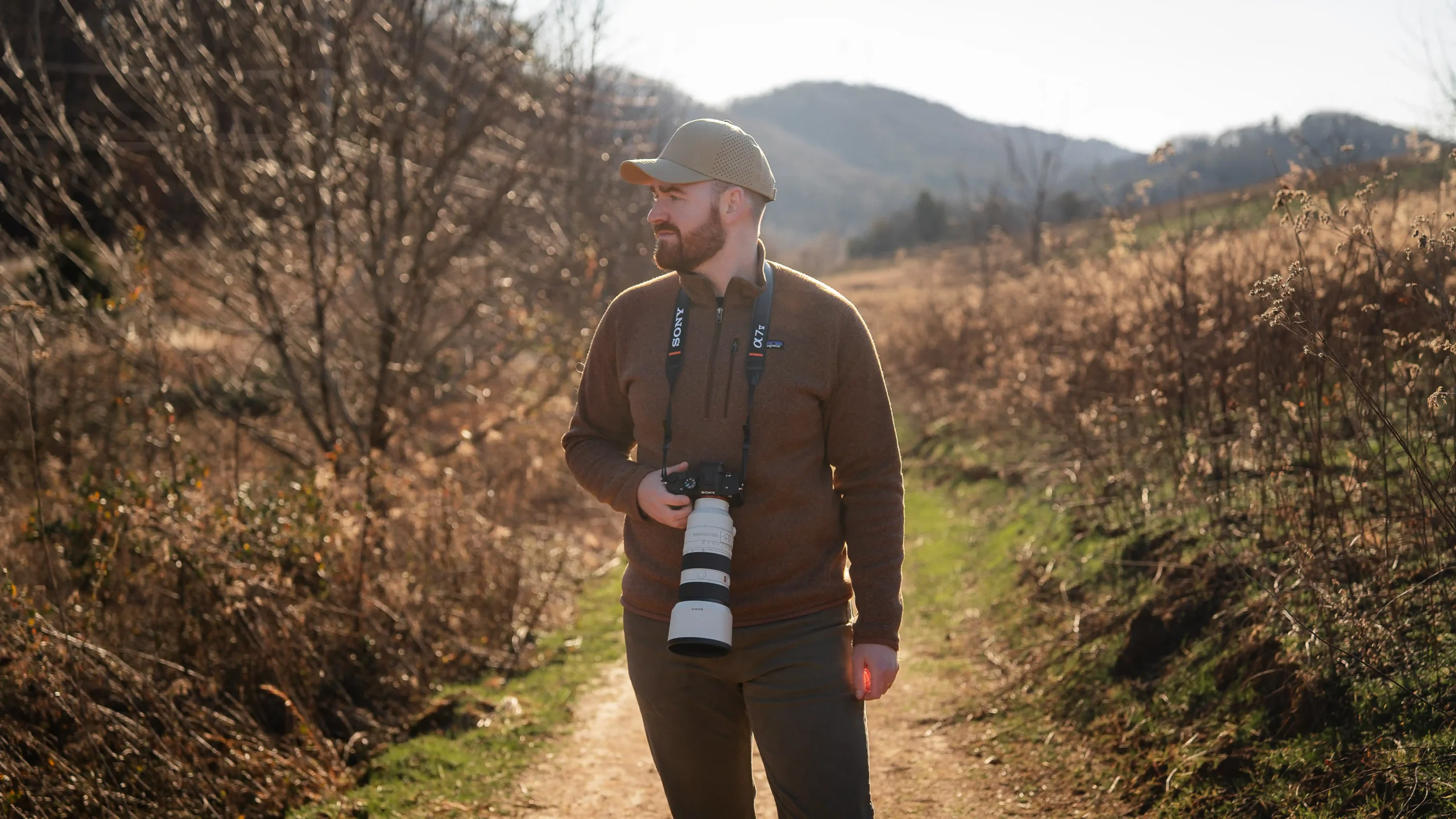 Outdoor photographer holding the Sony A7 V camera with branded strap in natural light