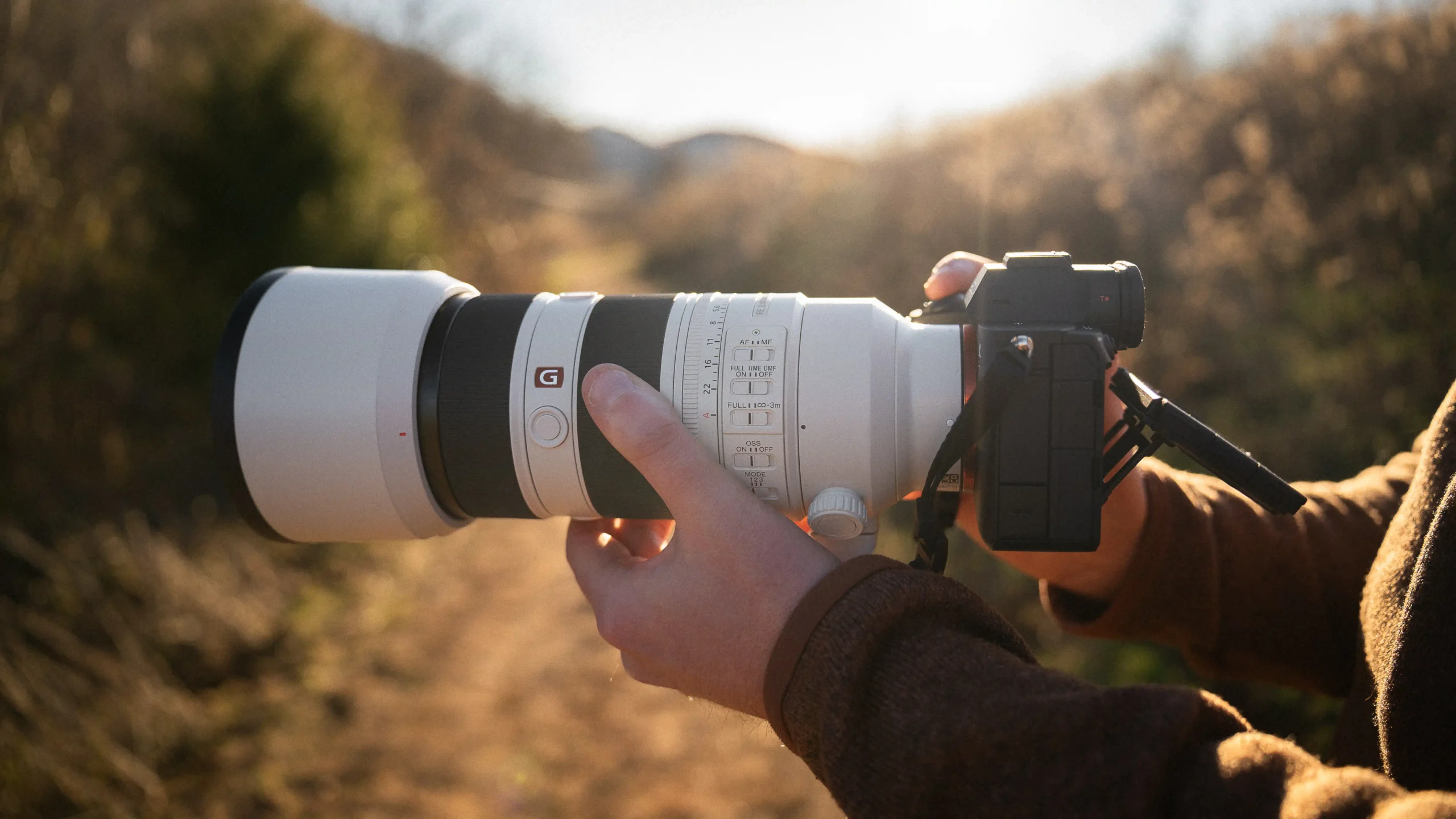 Adjusting settings on the Sony A7 V camera while shooting outdoors in warm sunlight