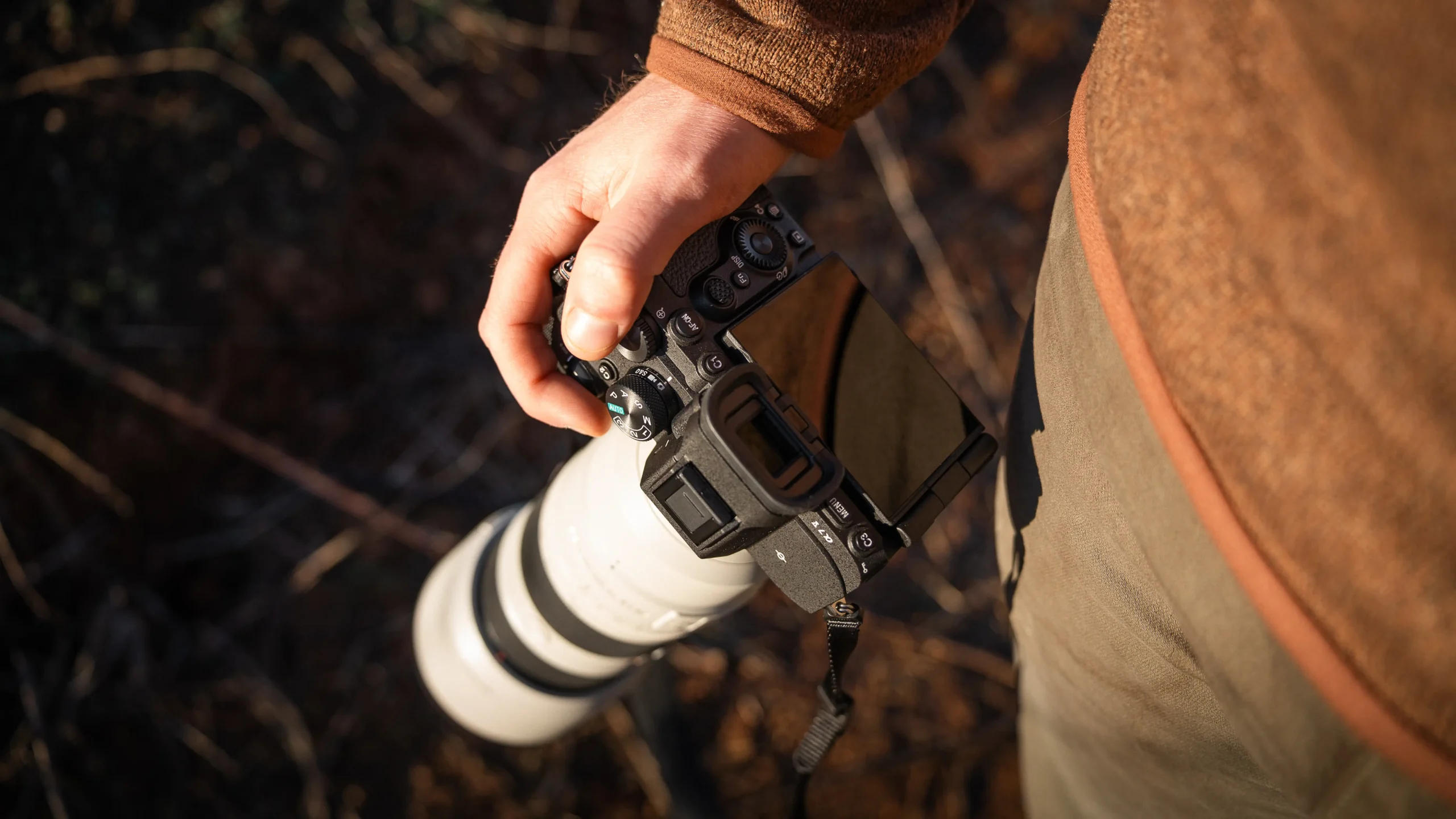 Top-down view of the Sony A7 V camera in hand showing the rear screen and electronic viewfinder