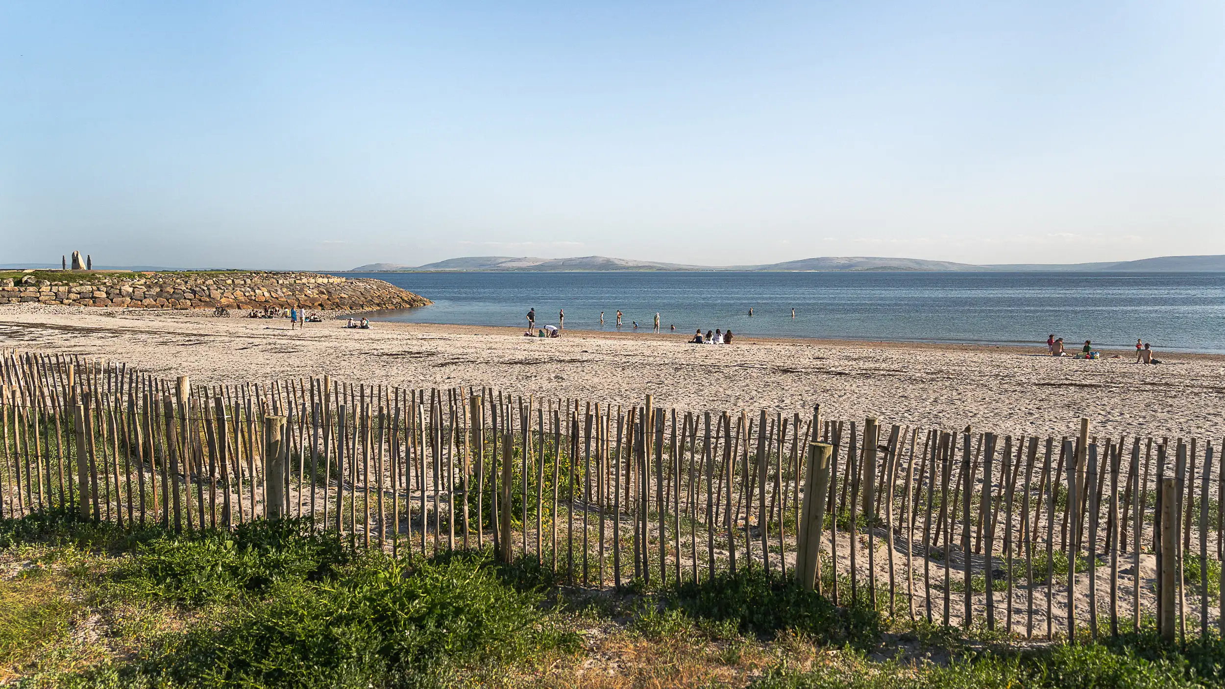 Visitors enjoying Grattan Beach in Galway with ocean views and distant mountains