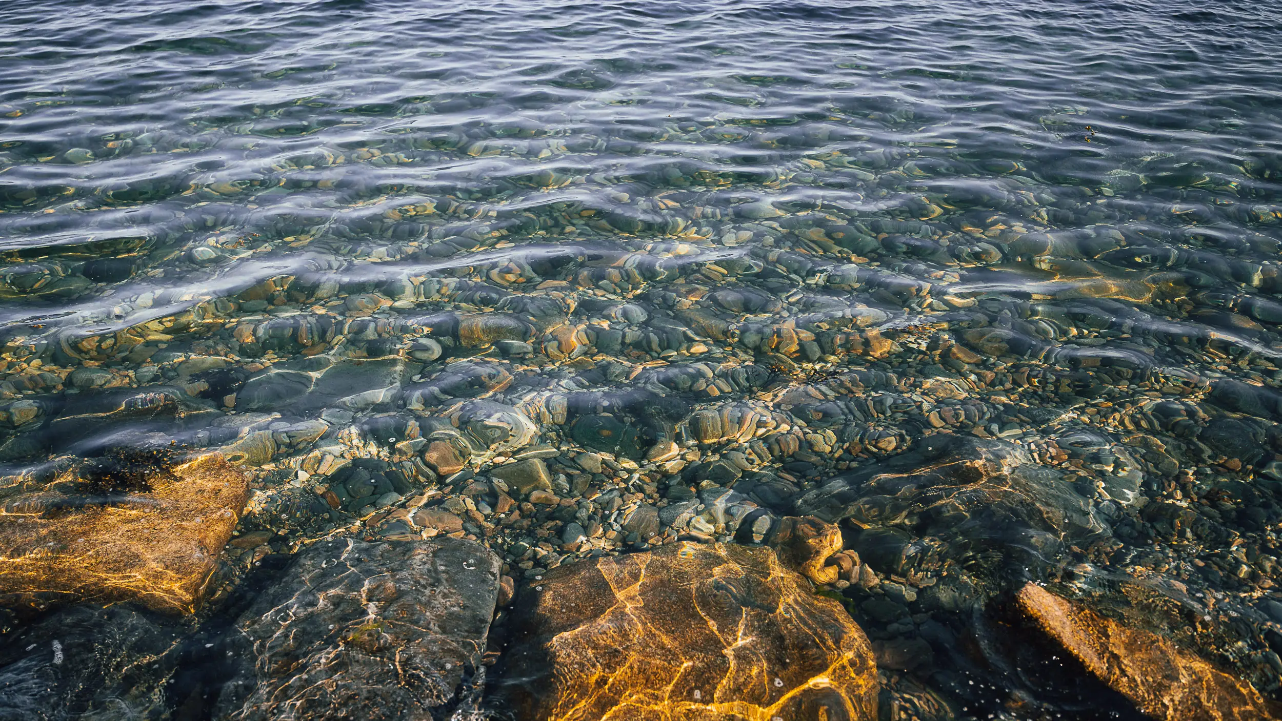 Clear coastal water revealing colorful rocks beneath the surface in Galway